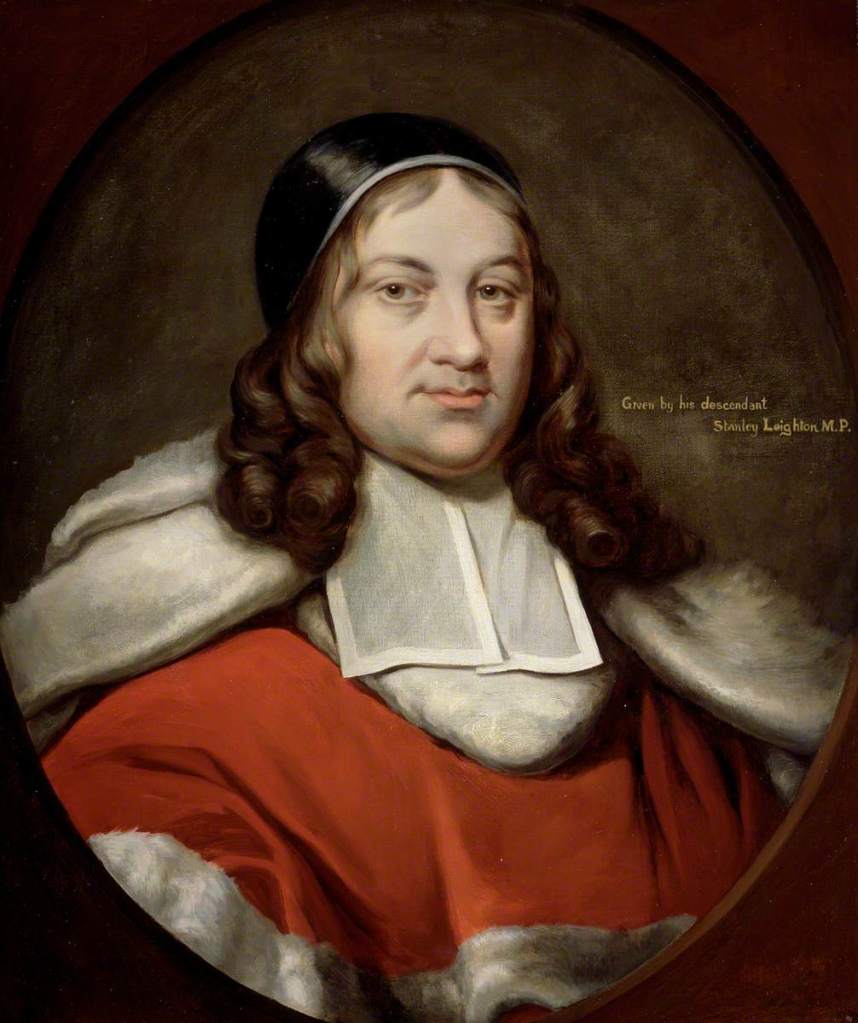 A oil portrait painting of the bust and head of Sir Job Charlton. Long brown curled hair. He is wearing a red robe with white trimmed fur. The writing 'Given by his descendant Stanley Leighton M.P. is written by his head.