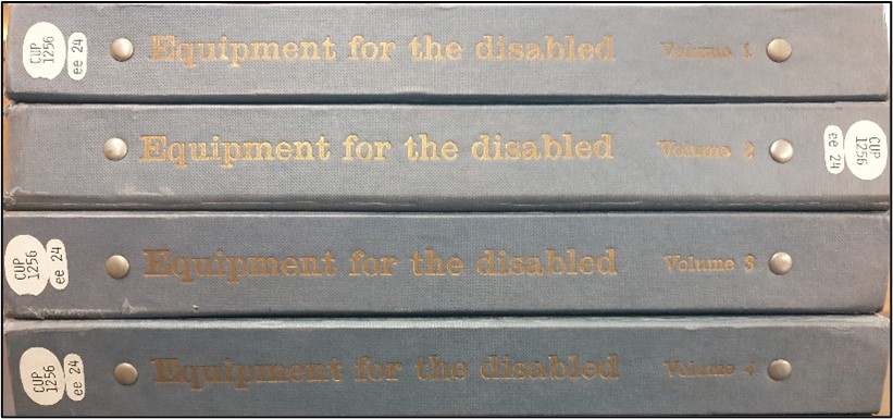 Four blue/grey folders/books stacked on top of eachother. The spine is in view. They are titled 'Equipment for the disabled' and it has (from top to bottom) volume 1, 2, 3, and 4.